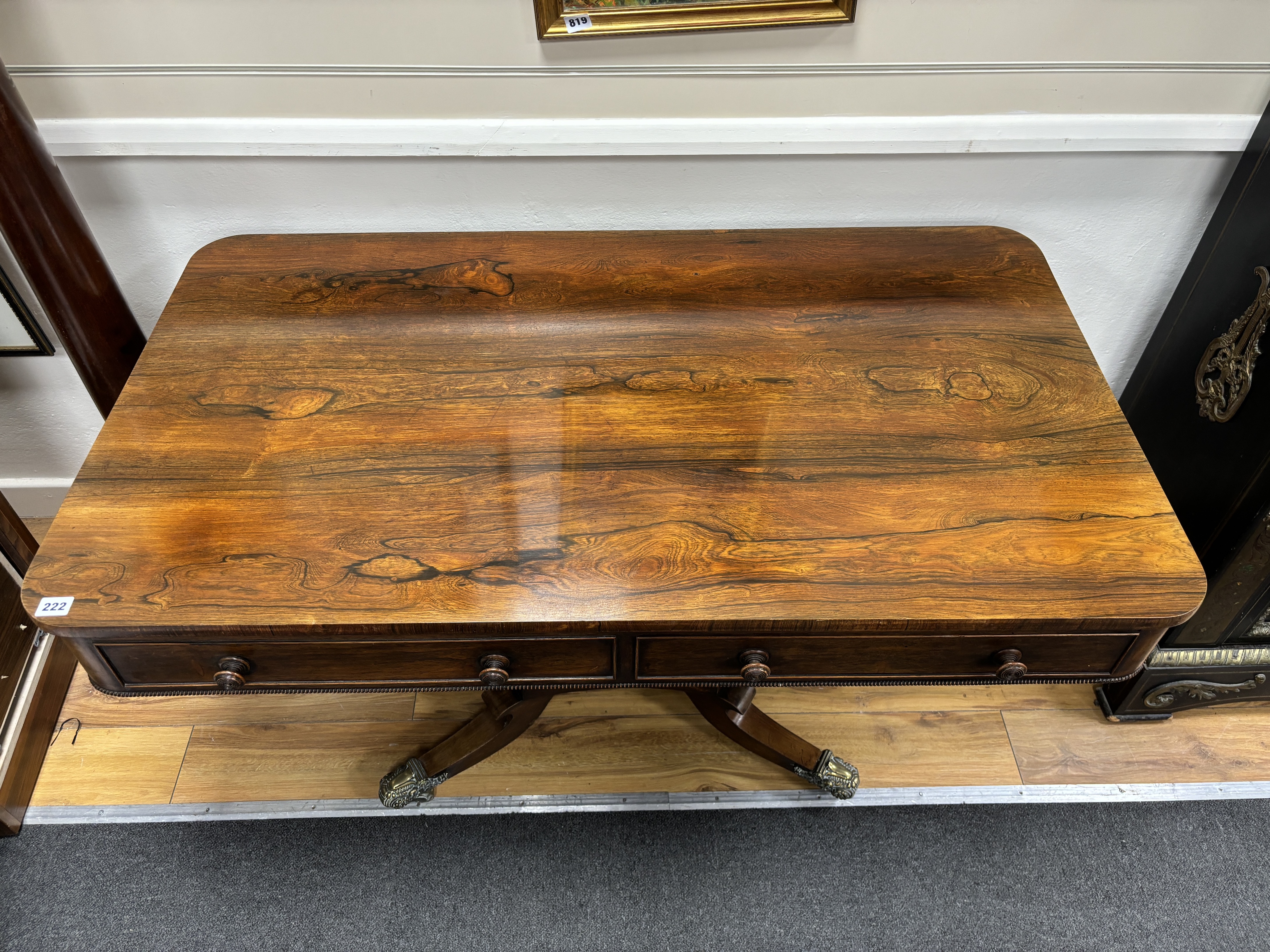 A Regency rectangular rosewood centre / library table, fitted two frieze drawers and two dummy drawers on single square tapered support, quadrapartite slab base and splayed legs with brass castors, width 123cm, depth 70c